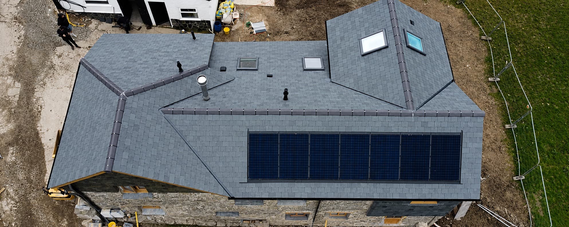 Aerial view of a new slate roof with solar panels on a Cornish stone property by NL Roofing