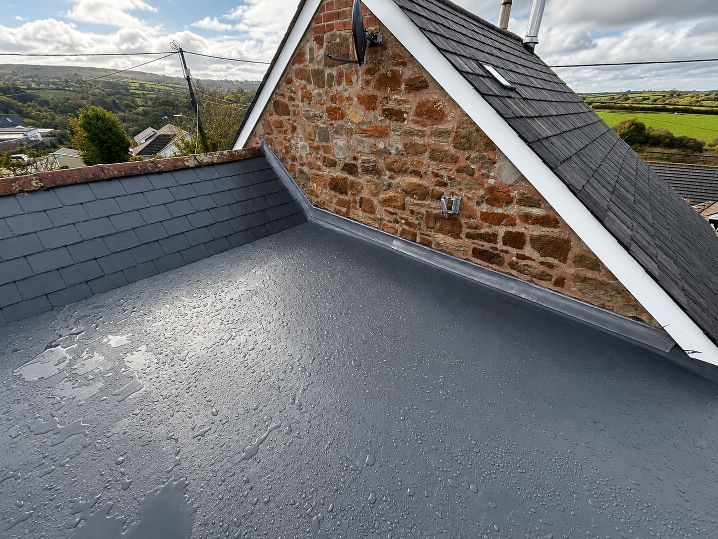 GRP flat roof installation alongside a slate pitched roof on a Cornish stone property by NL Roofing